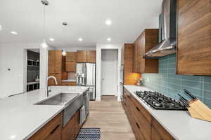 Kitchen featuring wood finish cabinetry, decorative light fixtures, light wood-style flooring, decorative backsplash, and stainless steel fridge with ice dispenser