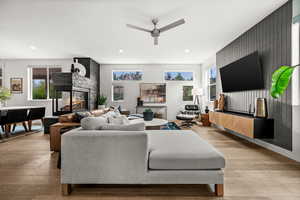 Living area featuring a multi sided fireplace, light wood-type flooring, ceiling fan, recessed lighting, and an accent wall