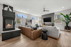 Living area with a fireplace, light wood-style flooring, ceiling fan, and recessed lighting
