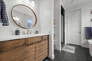 Primamry bathroom featuring vanity, dark tile patterned floors, and a freestanding tub