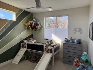 Bedroom with multiple windows, light colored carpet, and a ceiling fan