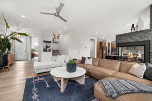 Living area with ceiling fan, a stone fireplace, wood finished floors, and recessed lighting
