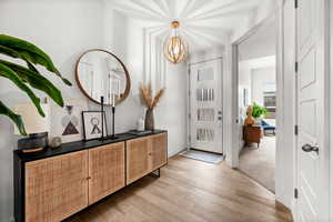 Foyer with light wood finished floors and suspended lighting
