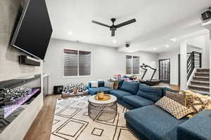 Living area featuring light wood-style flooring, ceiling fan, recessed lighting, and a glass covered fireplace