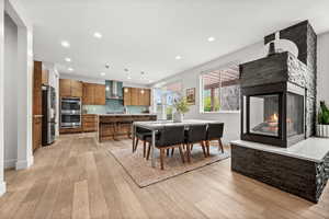 Dining room featuring a stone fireplace, light wood-style floors, and recessed lighting