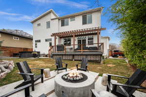 Rear view of property featuring a patio, a deck with mountain view, stucco siding, a hot tub, and a pergola