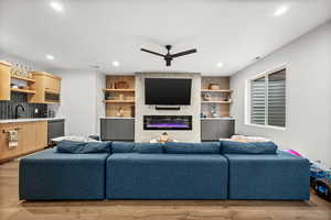 Living area featuring light wood-type flooring, a ceiling fan, a fireplace, and recessed lighting