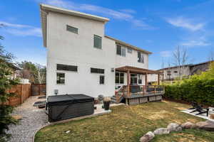 Rear view of house with a deck, a patio, stucco siding, a hot tub, and a fenced backyard