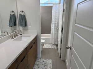 Full bathroom with vanity, dark tile patterned flooring, and shower / bathtub combination with curtain