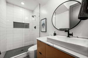 Bathroom with a stall shower, vanity, and recessed lighting