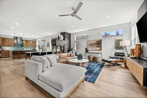 Living room with light wood-type flooring, ceiling fan, recessed lighting, and a fireplace