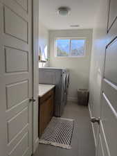 Laundry room with dark tile patterned flooring and washer and dryer