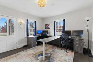 Office space with dark wood-type flooring and baseboards with a seperate entrance.