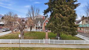 View of front of house with covered porch, a fenced front yard, and a chimney on Midway Main Street