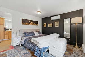 ADU bedroom featuring an ensuite bath, wooden walls, and a wall-mounted AC