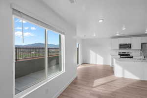 Kitchen featuring white cabinets, a mountain view, appliances with stainless steel finishes, light wood-type flooring, and recessed lighting