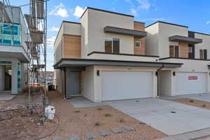 View of front of home with stucco siding, concrete driveway, and an attached garage