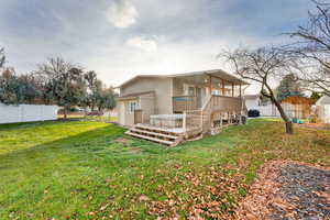 Rear view of property featuring a deck, a fenced backyard, and a shed