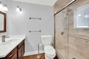 Full bath with vanity, a shower stall, and dark wood finished floors