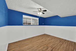 Spare room with wood finished floors, a textured ceiling, and ceiling fan