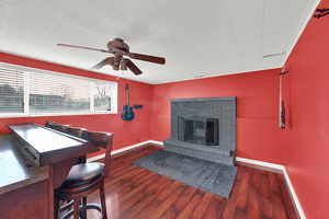 Living area featuring dark wood-style floors, a fireplace, and a ceiling fan