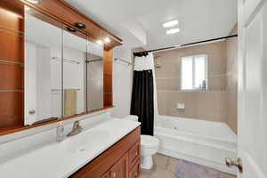 Bathroom featuring shower / bath combination with curtain, vanity, and light tile patterned flooring