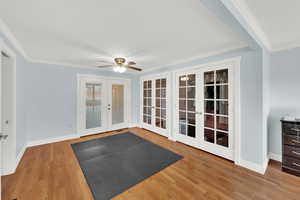 Exercise area with french doors, crown molding, light wood finished floors, and a ceiling fan