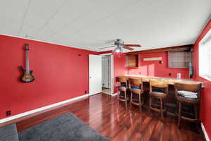 Indoor bar featuring dark wood-type flooring and ceiling fan