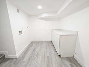 Laundry area with hookup for a washing machine, cabinet space, light wood-style floors, and recessed lighting