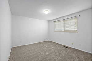 Empty room with a textured ceiling and carpet