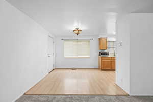 Unfurnished dining area with light wood-style flooring and light colored carpet