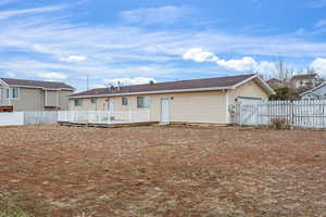 Back of property featuring roof with shingles, a wooden deck, and a gate