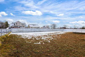 Snowy yard with a residential view and a fenced backyard