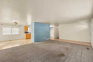 Unfurnished living room featuring light colored carpet and a textured ceiling