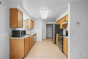 Kitchen with stainless steel appliances, light countertops, and light wood finished floors