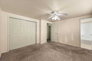 Unfurnished bedroom featuring carpet floors, a closet, a textured ceiling, and ceiling fan