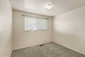 Unfurnished room featuring a textured ceiling and carpet