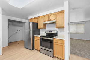 Kitchen with stainless steel appliances, light countertops, and light wood-type flooring