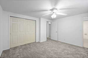Unfurnished bedroom with carpet flooring, a closet, and a ceiling fan