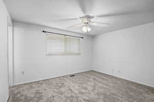 Carpeted empty room featuring a textured ceiling and ceiling fan