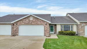 View of front facade featuring concrete driveway, a shingled roof, and a garage