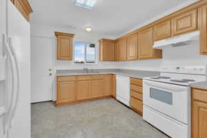 Kitchen featuring white appliances and light oak cabinets