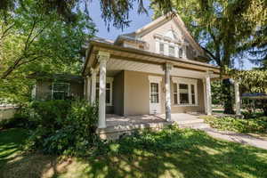 Rear view of property featuring covered porch, brick siding, and a lawn