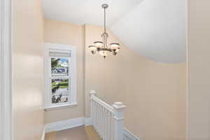 Stairway featuring baseboards and a chandelier