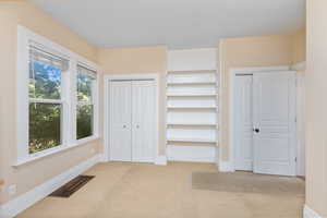 Unfurnished bedroom featuring multiple closets and light colored carpet