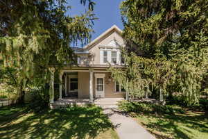 Victorian house featuring brick siding and a porch