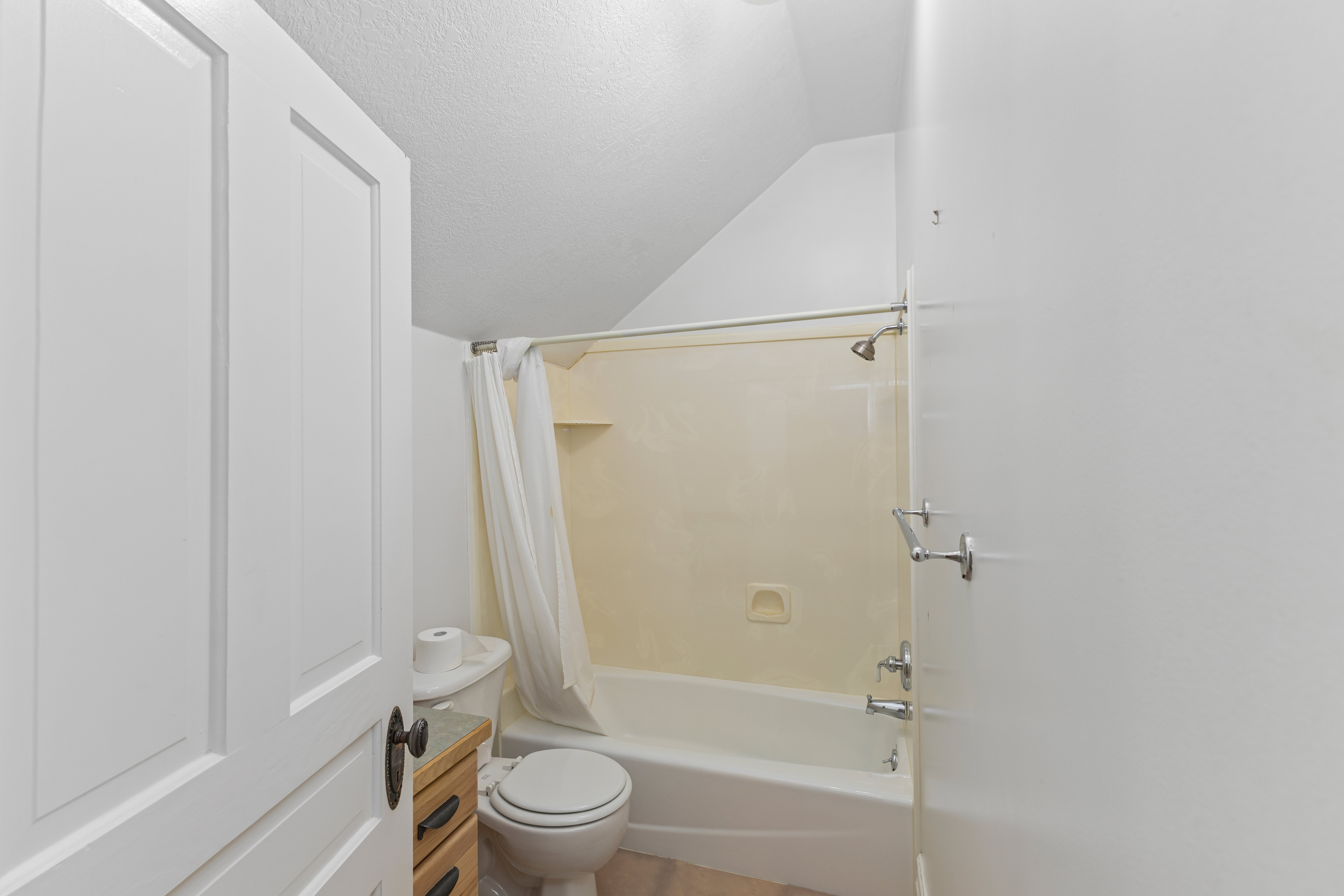 Full bath with shower / bath combination with curtain, vaulted ceiling, and a textured ceiling