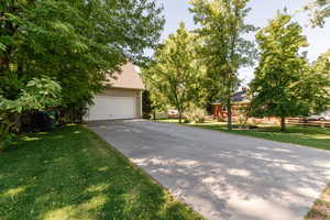 View of side of home featuring a yard, a garage, and concrete driveway