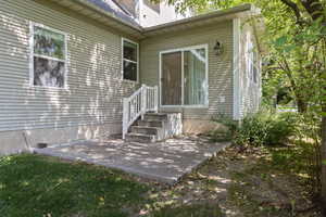Entrance to property with a patio, roof with shingles, and a chimney