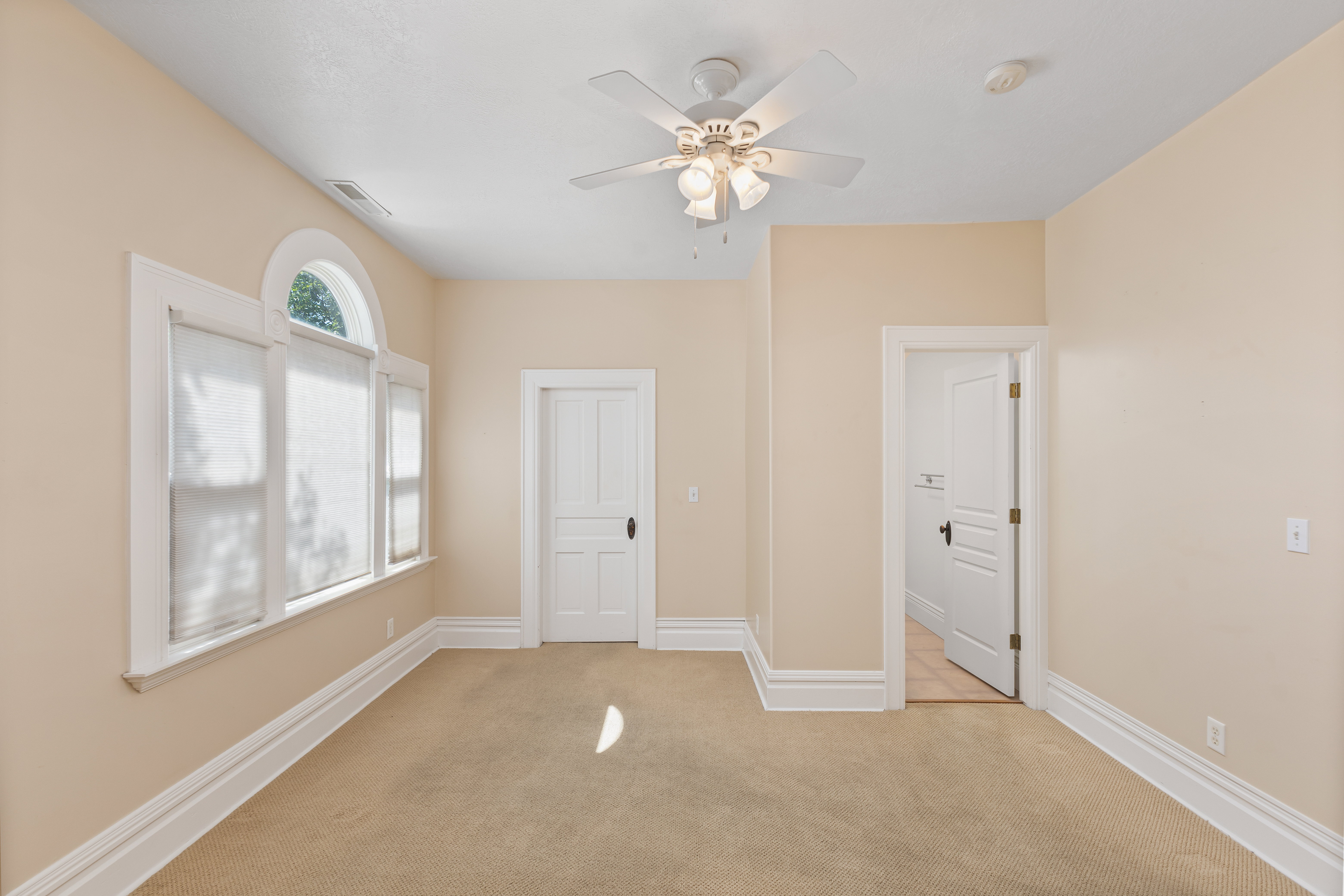 Unfurnished bedroom with light carpet and ceiling fan